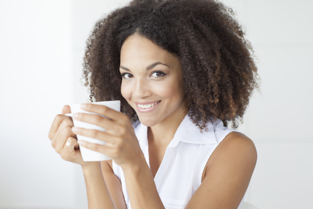 close up of young woman smiling and drinking coffee